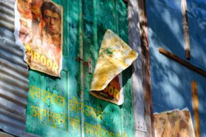 A photo of Indian film posters against a wooden wall painted in greens and blues