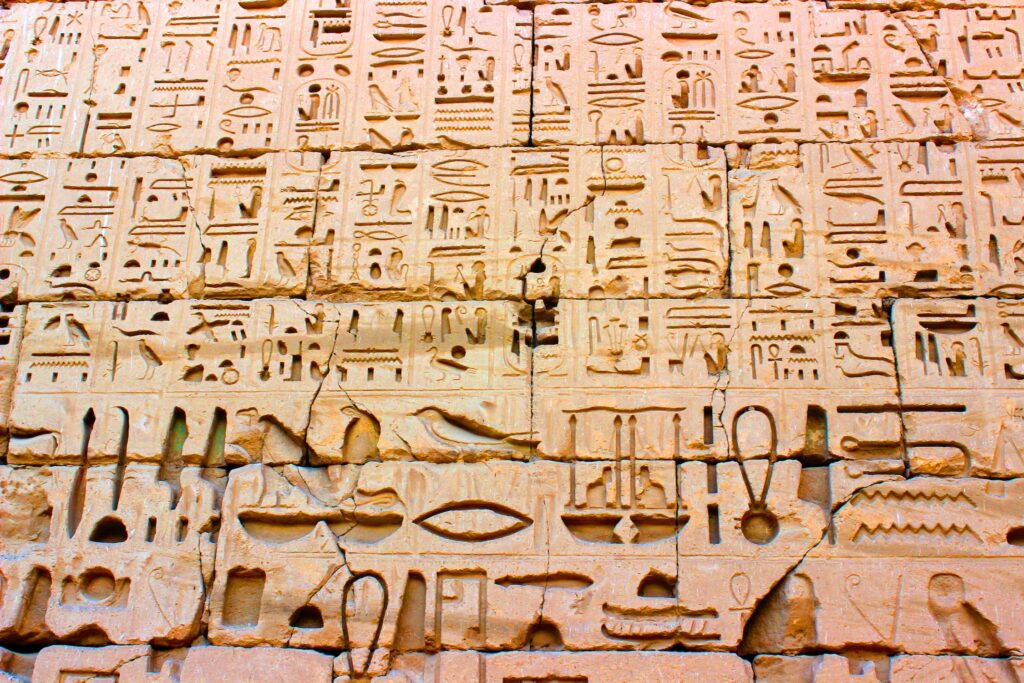 A photo looking up at a wall of hieroglyphics carved into a wall of sandstone